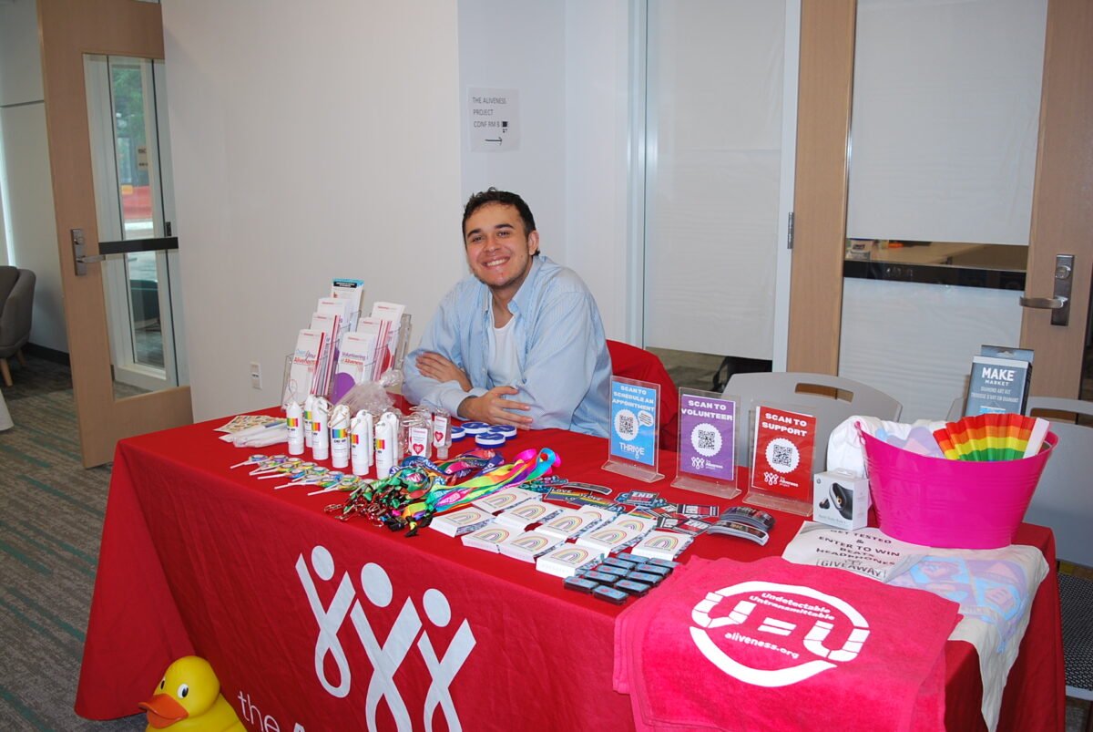 A person sits behind a table with pamphlets and information