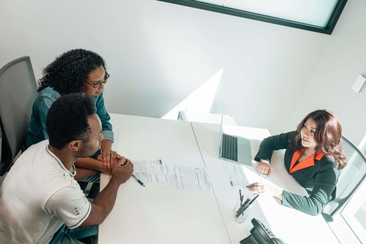 A man and a woman sit across from a woman working on a computer