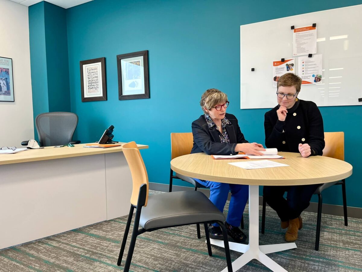 Two women sitting at a table looking at a folder